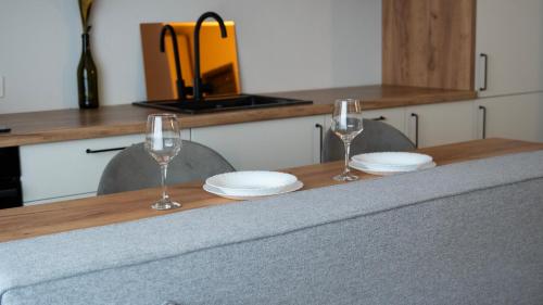 two wine glasses and plates on a wooden table at Cozy Apartments - Ared UTA Flat in Arad