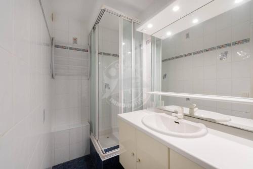 une salle de bain blanche avec un lavabo et une douche dans l'établissement AS9836 - P2 dans une résidence sur la plage avec belle vue sur le chenal et parking privé, au Grau-du-Roi