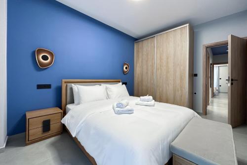 Un dormitorio con una gran cama blanca con paredes azules. en Dione Elegant Apartment Near Acropolis, en Atenas