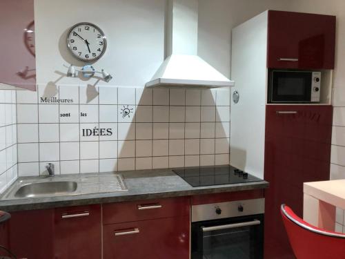 une cuisine avec un évier et une horloge murale dans l'établissement Au cœur de la perle du jura, à Champagnole