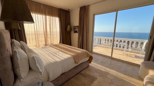 a bedroom with a bed and a view of the ocean at Villa La Falaise in Oualidia