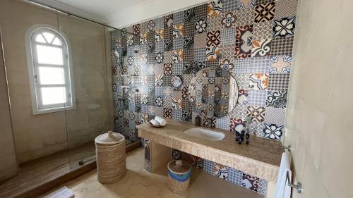 a bathroom with a sink and a mosaic wall at Villa La Falaise in Oualidia