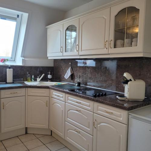 a kitchen with white cabinets and a sink at Ferienwohnung Meeresbrise in Aventoft