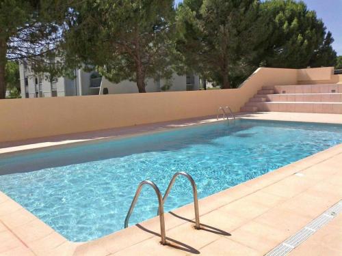 une piscine avec de l'eau bleue devant un immeuble dans l'établissement AS8314 - P2 Cabine dans une résidence avec piscine, parking privé et belle vue chenal, au Grau-du-Roi