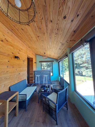Elle comprend un salon doté d'un mobilier bleu et de plafonds en bois. dans l'établissement Maison vue sur lac en moyenne montagne, à Pradelles-Cabardès