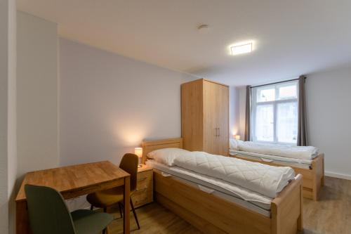 ein Zimmer mit zwei Betten und einem Schreibtisch und einem Tisch in der Unterkunft FeWo der 'Villa Ephraim' - James-von-Moltke-Str. in Görlitz