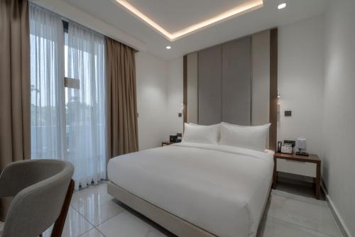 a bedroom with a large white bed and a chair at The Pelican Hotel Cantonments Accra in Accra