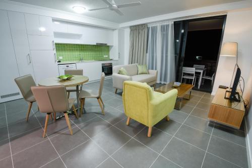 a living room with a table and chairs and a couch at Pacific Sands Apartments Mackay in Mackay