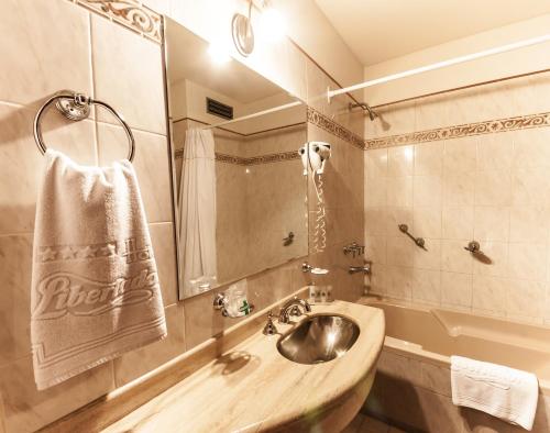 a bathroom with a sink and a tub with a towel at Hotel Libertador in Trelew