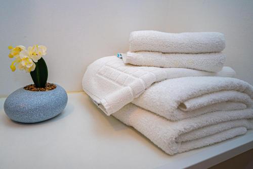 a pile of towels and a vase with a flower at FRIENDS RESIDENCE Apartments in Timişoara