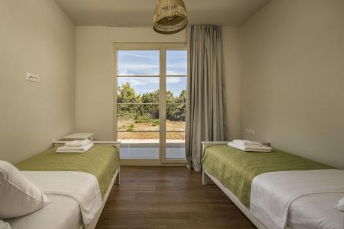 two beds in a room with a window at Villa Santa Lucia ZadarVillas in Turanj