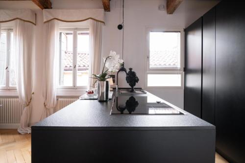 Una cocina con encimera negra y dos ventanas. en Rialto Terrace on the Grand Canal, en Venecia