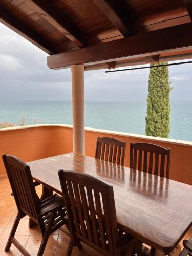 a wooden table and chairs on a balcony with the ocean at Apartments Vunić in Mošćenička Draga