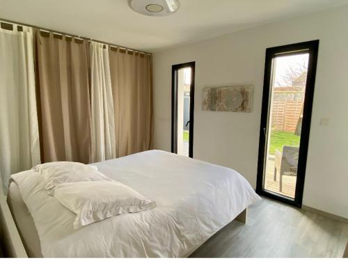 une chambre avec un lit blanc et une fenêtre dans l'établissement Ma Maison cote bassin, à Audenge