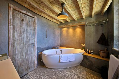 a bathroom with a white tub and a wooden door at Madada Mogador in Essaouira