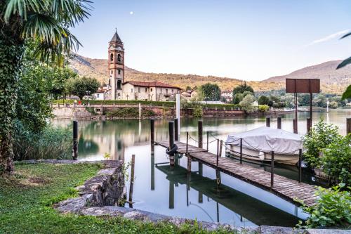a dock with a boat on the water with a church at Historical Caslano Apartments - Happy Rentals in Caslano