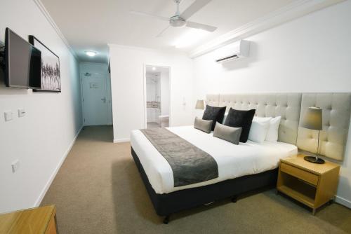 a bedroom with a large bed and a flat screen tv at Pacific Sands Apartments Mackay in Mackay
