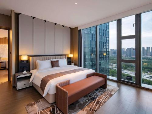a bedroom with a large bed and large windows at Grand Mercure Shenzhen Guangming in Shenzhen