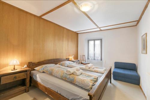 a bedroom with a large bed and a blue chair at Historical Caslano Apartments - Happy Rentals in Caslano