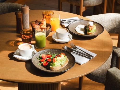 a wooden table with two plates of food on it at Mondrian Ibiza in Cala Llonga