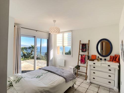 une chambre avec un lit, une commode et une fenêtre dans l'établissement Sur les hauteurs de Théoule villa avec une magnifique vue mer, à Théoule-sur-Mer