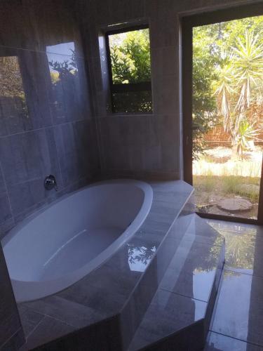 a large white tub in a bathroom with a window at Budias Guesthouse B&B in Kempton Park
