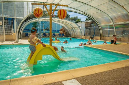 a child playing on a slide in a swimming pool at ZEcamping animé piscine couverte club enfant animations dog friendly in La Faute-sur-Mer