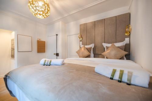 - une grande chambre blanche avec un grand lit et des oreillers dans l'établissement CIA - Studio de l'Étoile, à Paris