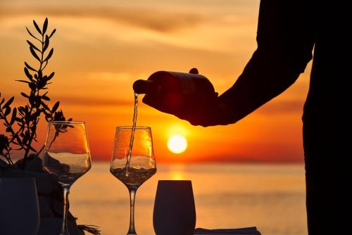 a person is pouring wine into glasses at sunset at Icon Suites by the sea in Potos