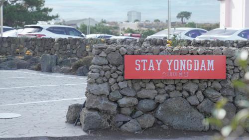 a sign on a stone wall with a parking lot at Stay Yongdam in Jeju