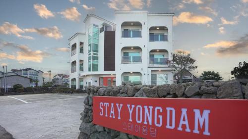 a building behind a stone wall with a sign in front at Stay Yongdam in Jeju