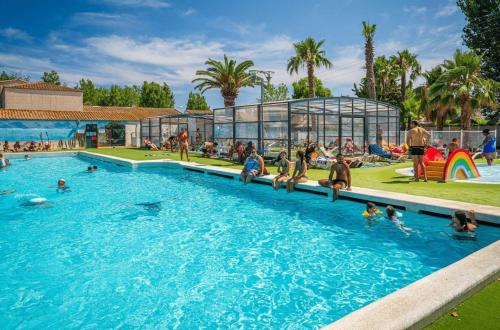 un groupe de personnes dans une piscine d'un complexe hôtelier dans l'établissement Camping - Piscine - ccagefg, à Portiragnes