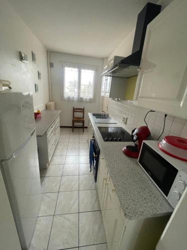 Il comprend une cuisine avec des appareils électroménagers blancs et du carrelage blanc. dans l'établissement Appartement spacieux à 2km du circuit, proche tram, circuit à 8 en tram, au Mans