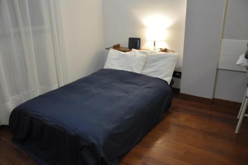 een slaapkamer met een bed met een blauwe deken en een lamp bij A casa di A in Milaan