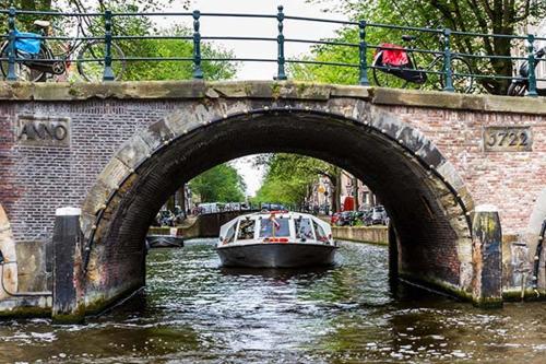 a boat traveling down a river under a bridge at Houseboat Maatrollie NS002 in Monnickendam