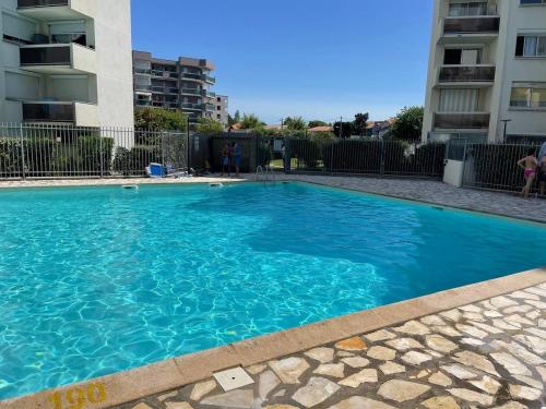 une grande piscine bleue devant un immeuble dans l'établissement Port City Arcachon Parking-Piscine, à Arcachon