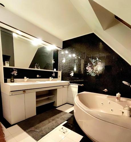 La salle de bains est pourvue d'une baignoire blanche, d'un lavabo et d'une baignoire. dans l'établissement Villa des étoiles, à Dole