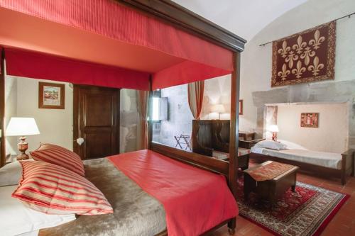 a bedroom with a large canopy bed with red sheets at Chateau des Ducs de Joueuse, BW Signature Collection in Couiza