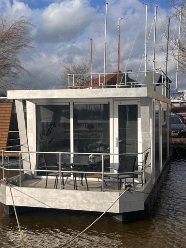 a boat with tables and chairs on the water at Houseboat Oslo perfect voor bezoek Amsterdam in Monnickendam