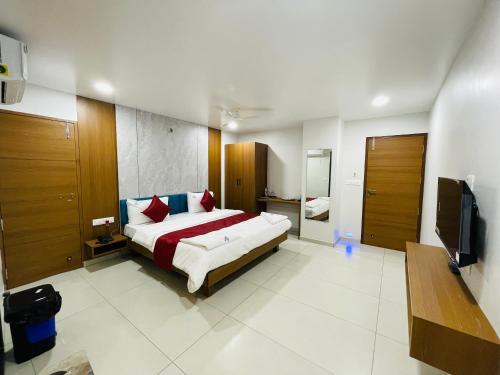 a bedroom with a large bed and a television at Hotel Coastal Empire in Belgaum