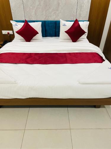 a bed with red and blue pillows on it at Hotel Coastal Empire in Belgaum
