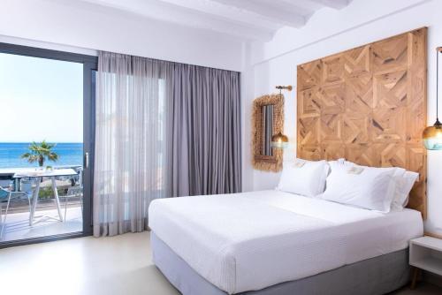 a bedroom with a bed and a balcony with the ocean at Icon Suites by the sea in Potos