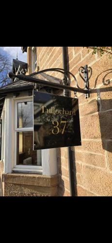a sign on the side of a building with a window at Tullochard Guest House in Alness