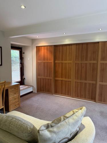 a living room with wooden cabinets and a couch at The Stables East Lodge Country House in Great Rowsley