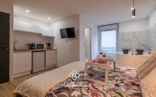 Il comprend une cuisine et un salon avec un lit et une table. dans l'établissement Love au Mans - Sauna et Jacuzzi inclus, au Mans
