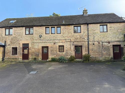 an old brick house with a parking lot at The Stables East Lodge Country House in Great Rowsley