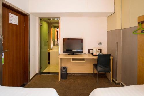 a room with a desk with a television and a chair at Motel Shanghai Pudong Lianyang New International Expo Centre in Shanghai