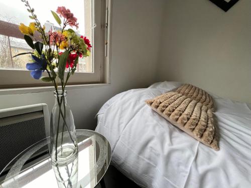 - un vase avec des fleurs et un oreiller sur le lit dans l'établissement Saint Exupery Parking Wifi Un Séjour à Part, à Thionville