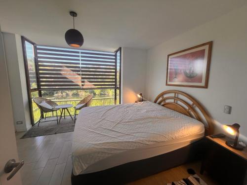 Schlafzimmer mit einem Bett und einem Fenster mit einem Stuhl in der Unterkunft Oceana Suites Remanso de Algarrobo in San Antonio