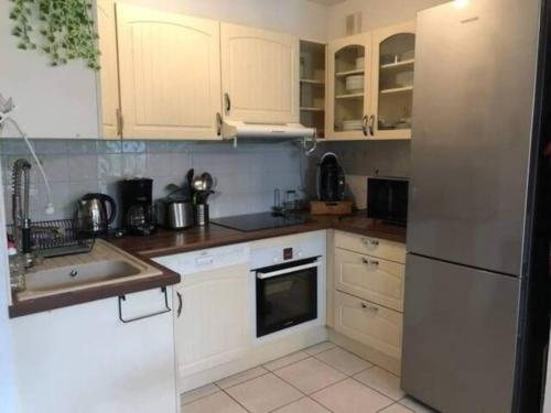 une cuisine avec des armoires blanches et un réfrigérateur en acier inoxydable dans l'établissement Le Clos d'Alice, à La Teste-de-Buch